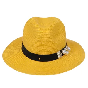 Détail d'un chapeau Panama en paille jaune avec ruban noir et fleur de perles élégante