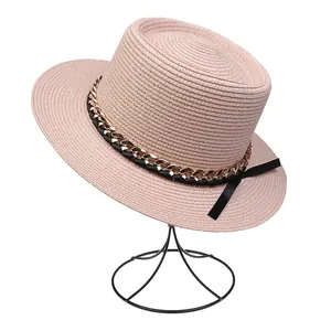 Detailansicht eines rosa Strohhutes mit goldener Kette und schwarzer Schleife am Band