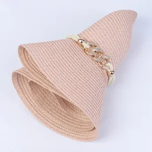Detail of foldable pink straw hat showing textured weave and rhinestone metal chain