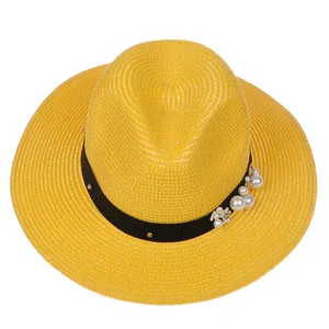 Détail d'un chapeau Panama jaune en paille avec ruban noir, perles et touches florales