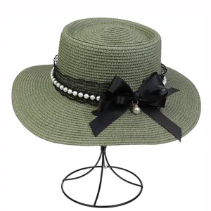 Detailed texture of green straw boater hat with lace band, white pearls and black bow