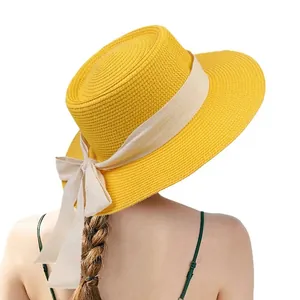 Elegant bright yellow flat top straw hat with wide cream ribbon and bow for summer beach