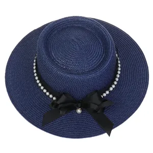 Detailed texture of navy woven straw hat with elegant white pearls and a satin bow knot