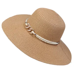Detail view of khaki straw hat featuring golden chain and white rope decorative accents