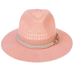 Close-up of pink woven straw fedora featuring white rope band and gold chain buckle detail