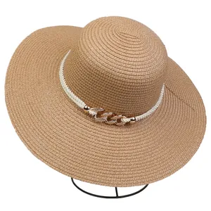 Macro view of wide-brim straw hat featuring white braided rope and golden metal chain detail