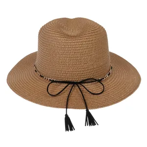 Detail of khaki straw sun hat with gold chain, black bow, and decorative tassels