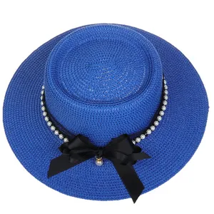 Detailed top view of blue straw boater hat featuring black ribbon and white pearls