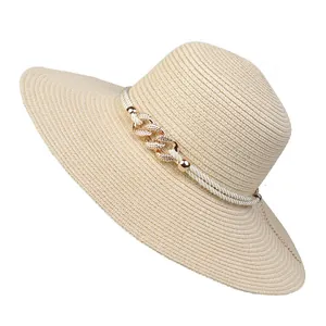 Close-up of woven straw sun hat with decorative white rope and gold metal chain link details