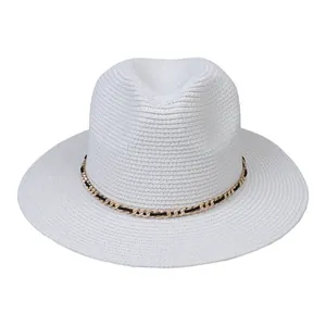 Close-up of white woven Panama hat detail with golden metal chain and black ribbon band