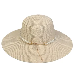 Detail of beige straw sun hat with woven white rope, gold buckle and adjustable chain