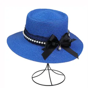 Detail of royal blue straw hat featuring black lace, white pearls, and a satin bow