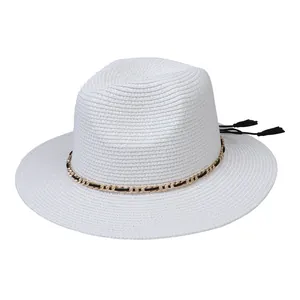 Detail of white straw Panama hat featuring a black gold chain band and tassels
