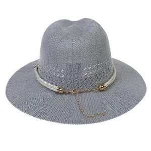 Detail of grey straw fedora hat with white rope trim and golden metal chain link