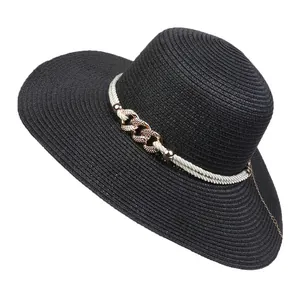 Detail of black wide brim straw hat featuring white rope and gold metal chain link