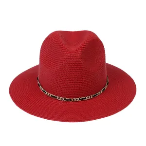 Detail of red panama hat featuring woven texture and decorative gold metal chain link