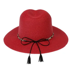 Detailed texture of red straw fedora with golden chain and black tassel accents