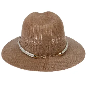 Close-up of brown straw fedora with white braided rope and golden metal buckle details