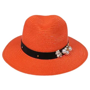 Détail d'un chapeau Panama orange avec ruban noir, clous dorés, perles et fleurs