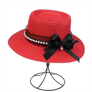 Detail showing red straw hat with black lace trim, pearls, and a large satin bow decoration