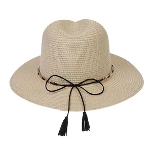 Detail of light beige Panama hat featuring fine straw weave with gold chain and tassels