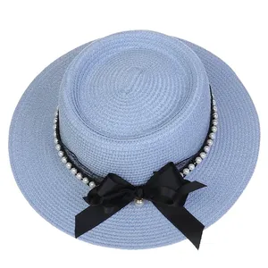 Detail of light blue straw hat featuring black lace, white pearls and a large satin bow
