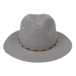 Detail view of a grey woven Panama hat featuring a black and gold metal chain band