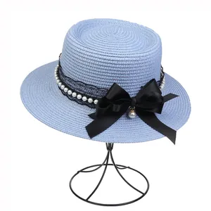 Detail view of light blue straw sun hat with black lace ribbon, pearls, and a large bow