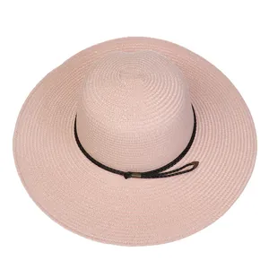 Detail of light pink wide brim straw sun hat with woven texture and black ribbon cord