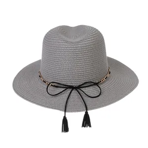 Detail of gray wide-brim straw hat featuring gold chain and black tassel bow decoration