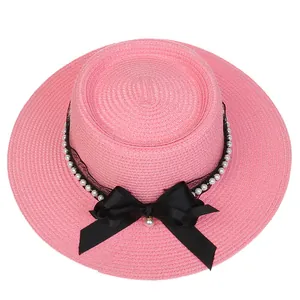 Detailed view of pink boater hat with black lace, pearls and large satin bow