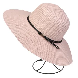Detail of pink straw sun hat showing woven texture and black ribbon with metal buckle