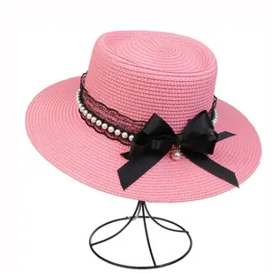 Detailed texture of pink straw sun hat with black lace, pearls and silk bow decoration
