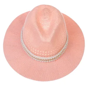Close-up of pink woven straw Fedora hat featuring elegant pearl and gold chain decorative band