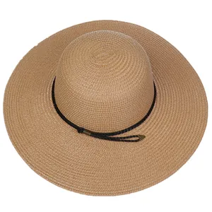 Close-up of woven straw hat texture with black decorative cord and golden metal tips