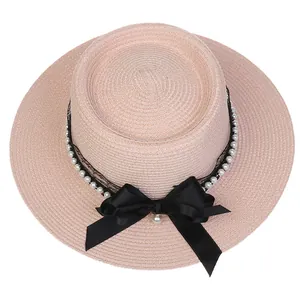 Detail of pink boater hat featuring black lace ribbon, pearl trim and satin bow