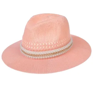 Detail of orange-pink straw hat featuring elegant pearl and gold chain trim
