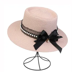 Detail of light pink straw hat with black lace, elegant pearls and a satin ribbon bow
