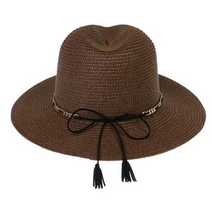 Close-up of brown straw Panama hat with gold chain, black bow, and decorative tassels