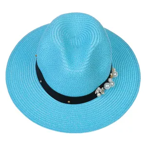 Détail d'un chapeau Panama bleu avec ruban noir orné de perles blanches et accents floraux