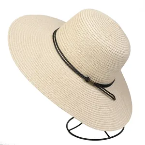 Detail of wide brim straw hat featuring black rope trim and fine woven texture