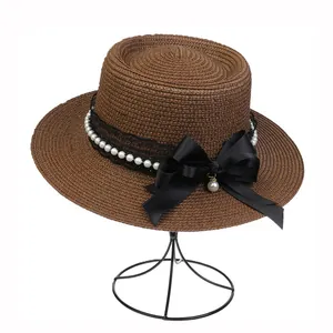 Detail of woven boater hat with black lace, pearls and a large satin bow decoration
