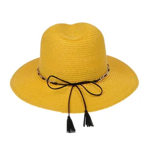 Detail of yellow woven straw hat featuring a gold chain and tassel bow decoration