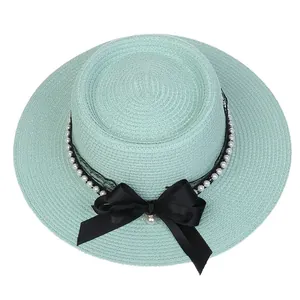Detailed macro view of the light green straw hat with a black bow and pearl decoration