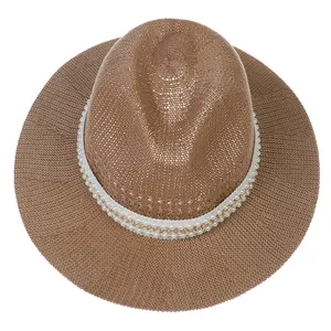 Detailed weave of brown straw hat featuring white faux pearls and a gold chain strap