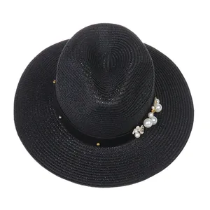 Détail d'un chapeau Panama noir orné de perles blanches et de petites fleurs
