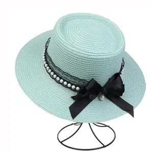 Detailed macro view of mint green straw hat with black lace, pearls, and a silk bow