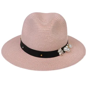 Vue détaillée du chapeau de paille rose avec ruban noir, perles et décor floral