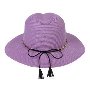Close-up of light purple straw sun hat featuring a gold chain, black bow, and tassels