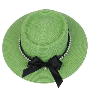 Detail view of woven green straw hat with white pearls and black ribbon bow decoration
